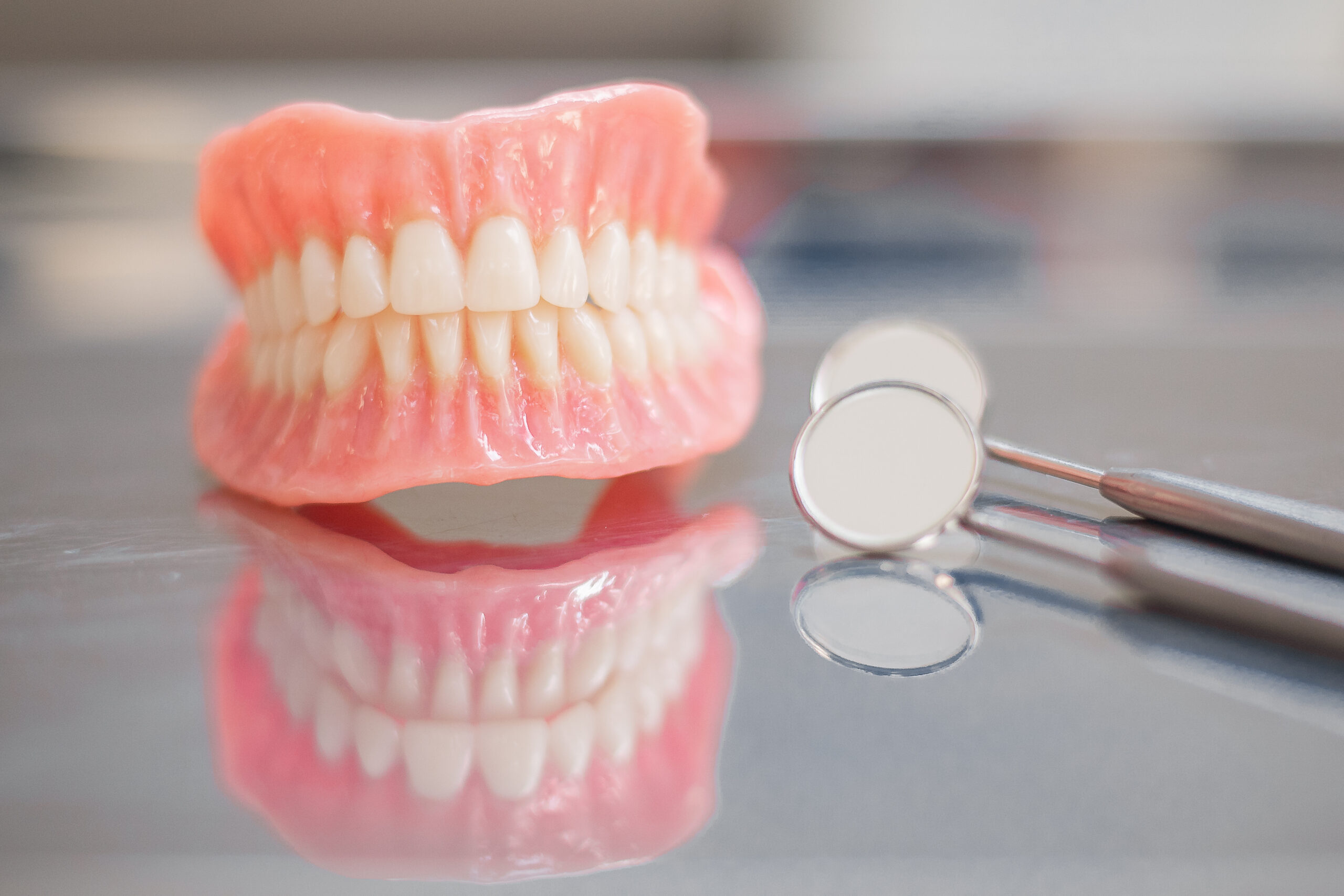 Two dentures. Instruments and dental hygienist checkup concept with teeth model dentures and mouth mirror. Regular dentist checkups