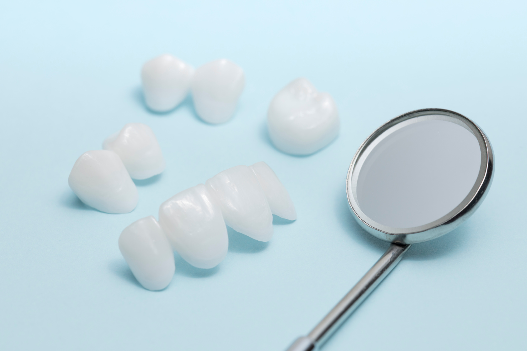 Dental mirror and dentures on a light blue background